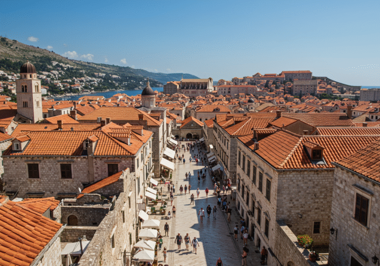 A bright summer day in the historic Old Town of Dubrovnik, Croatia, with the ancient city walls and iconic red-tiled roofs bathed in sunlight. A moderate number of diverse visitors calmly walk along the pristine cobblestone streets, enjoying the serene atmosphere and the majestic architecture. The sparkling blue Adriatic Sea is visible in the background, reflecting the clear sky. The scene conveys a sense of quality and a balanced, unhurried tourist experience.