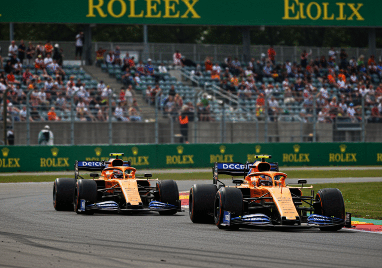 A dynamic, low-angle shot captures Lando Norris in his McLaren Formula 1 car narrowly leading Oscar Piastri's McLaren car during a high-speed duel at Turn 1 of the Hungaroring circuit, Hungary, on August 3, 2025. Piastri's car is seen making an aggressive, high-risk overtaking attempt, with a faint wisp of tire smoke or a slight blur suggesting the sharp braking maneuver to avoid collision with Norris. Bright, clear daylight illuminates the asphalt track and surrounding grandstands. The two cars are incredibly close, emphasizing the intense, wheel-to-wheel racing action. Realistic editorial sports photography.